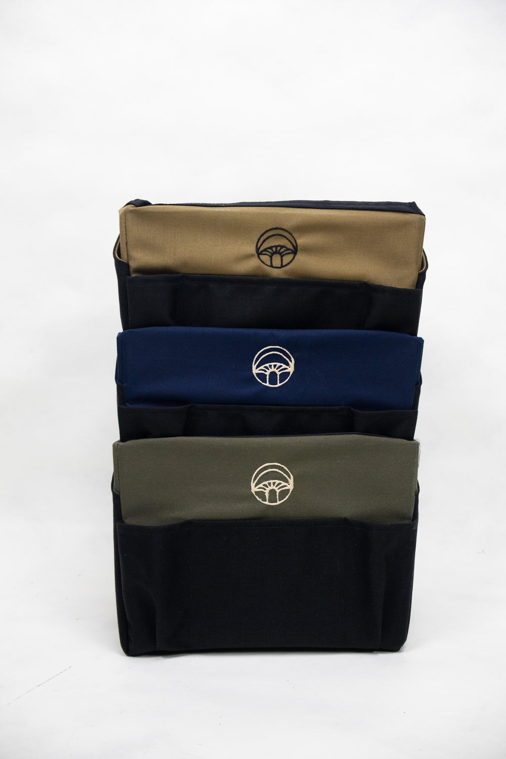 Stack of three pouches in beige, blue, and green with a logo on a white background
