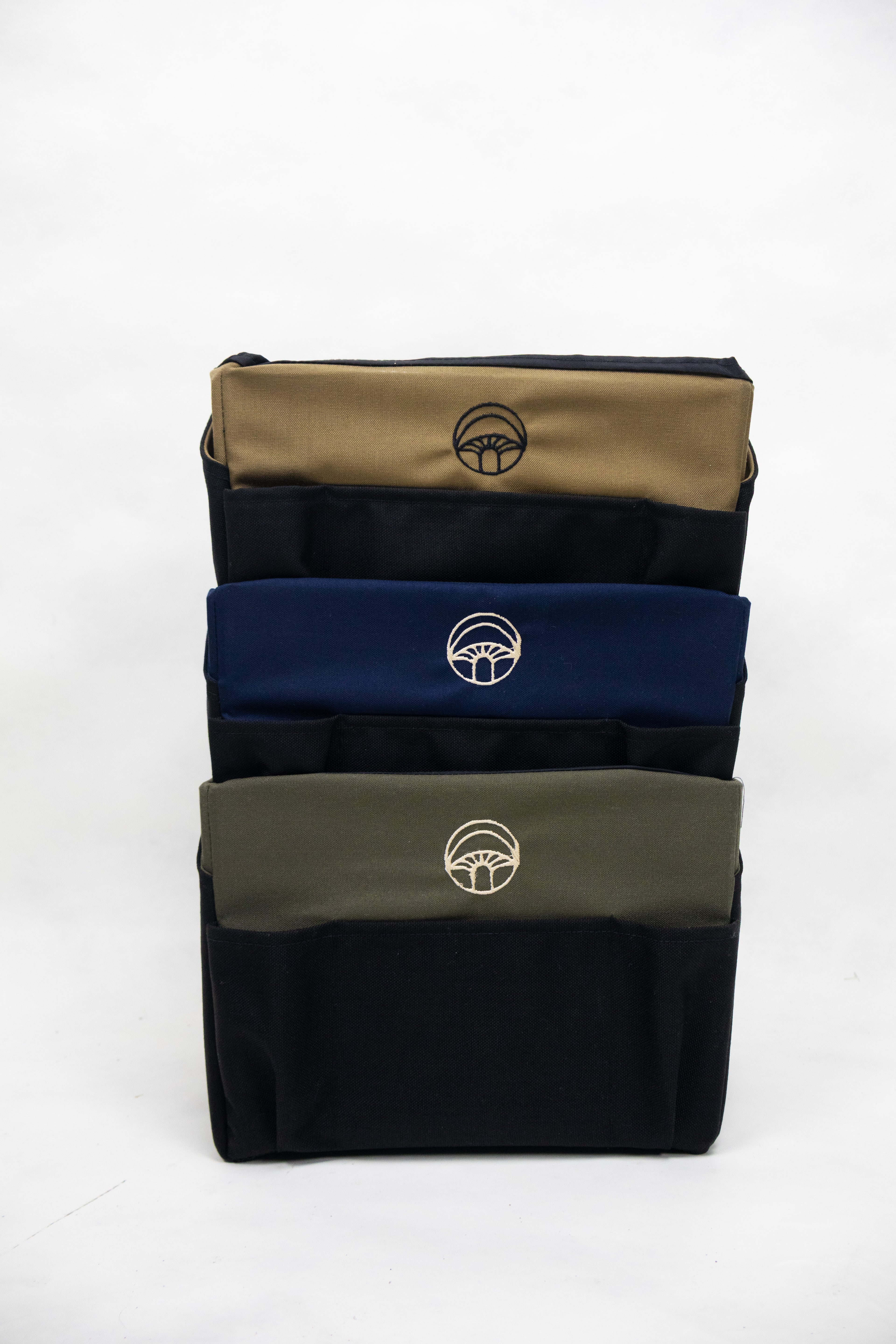 Stack of three pouches in beige, blue, and green with a logo on a white background