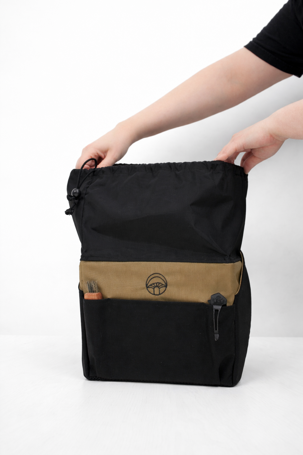 Black and brown backpack held by a person on a white background