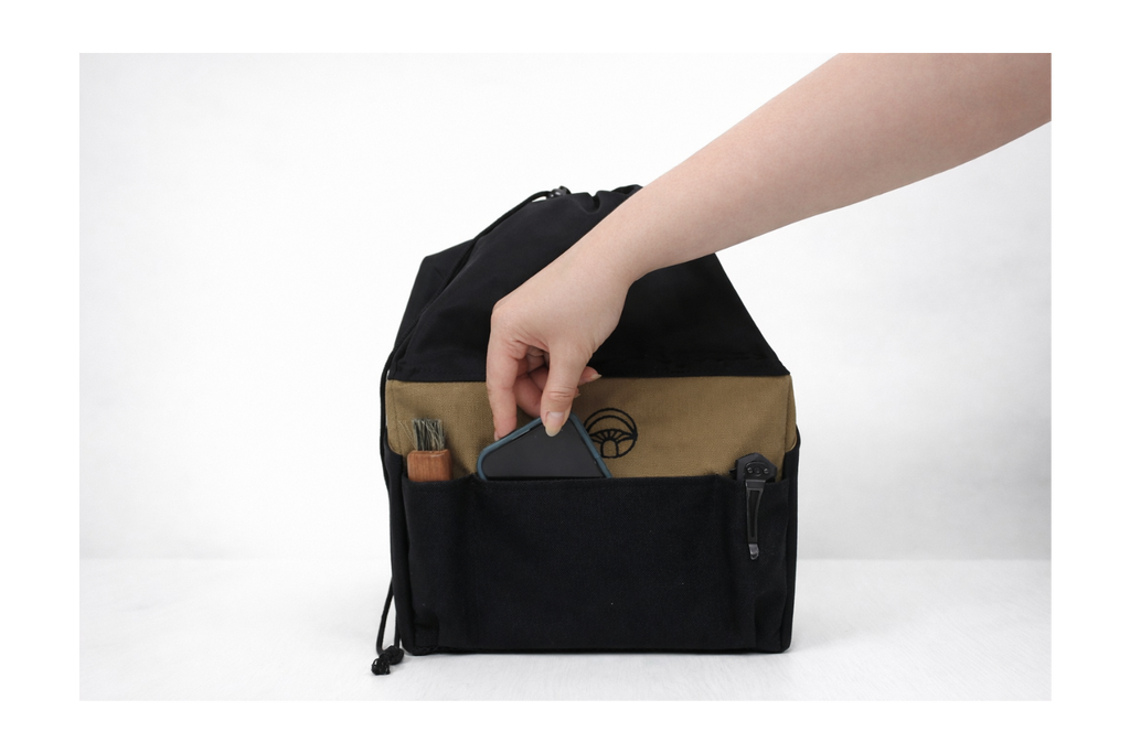 Person putting in a phone in a black and brown bag with a white background