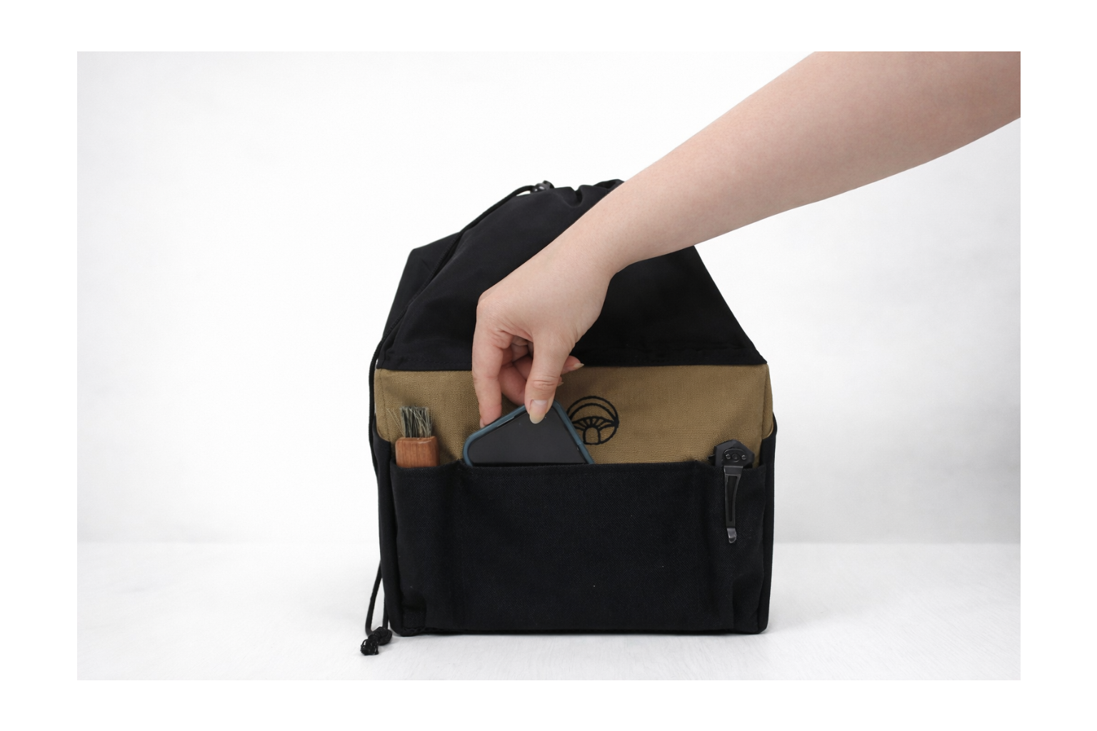 Person putting in a phone in a black and brown bag with a white background