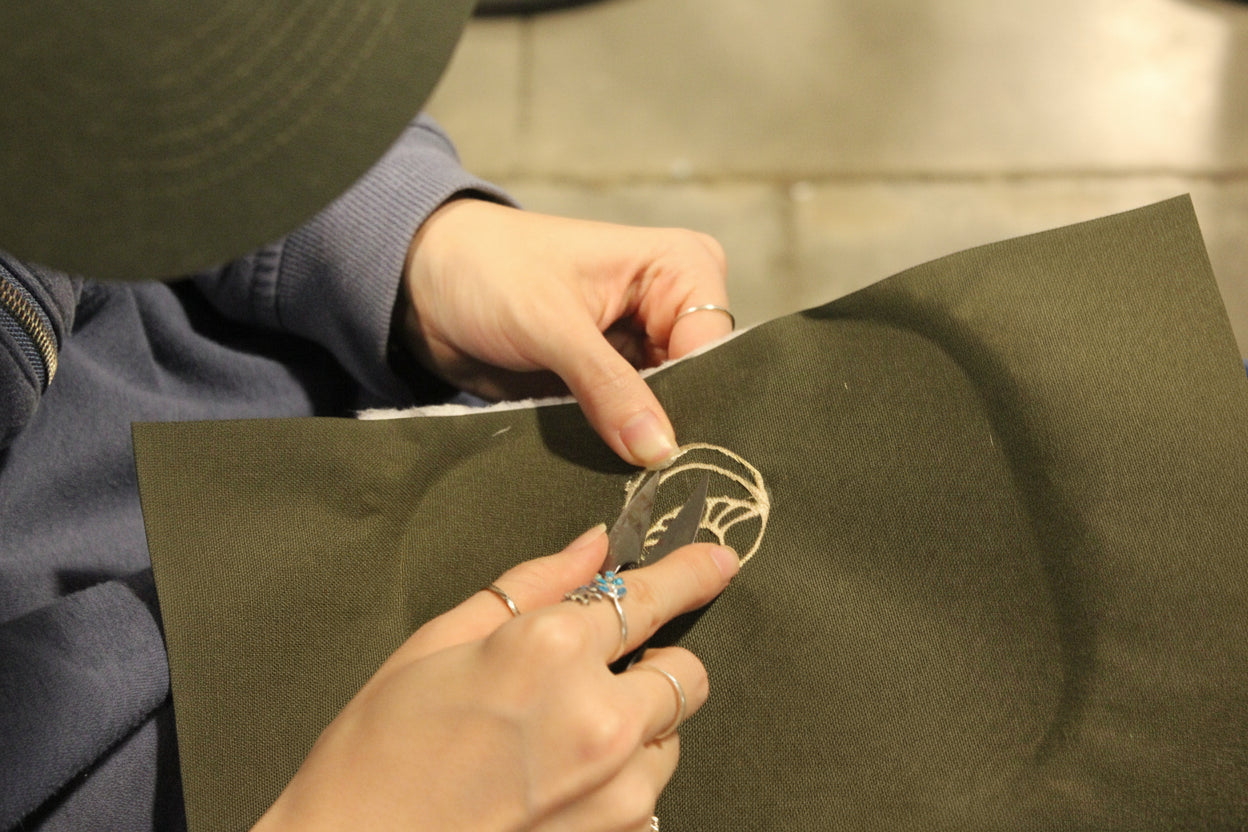 Person holding a piece of fabric with a logo, wearing rings.